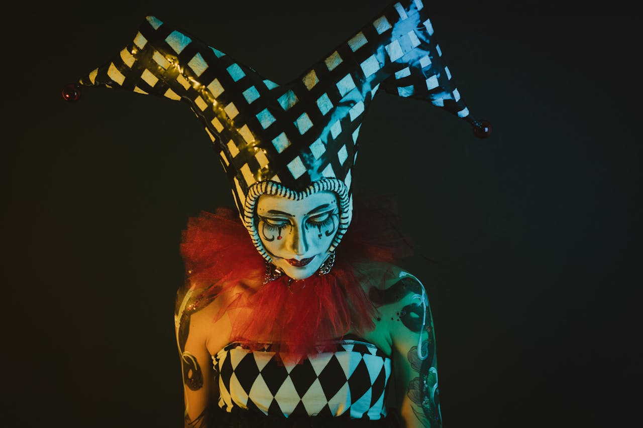 A dark, moody portrait of a model in a harlequin costume with dramatic makeup, perfect for Halloween themes.